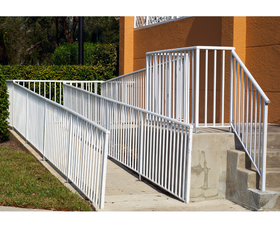 Concrete and metal wheelchair ramp leading up to a building entrance with concrete steps.