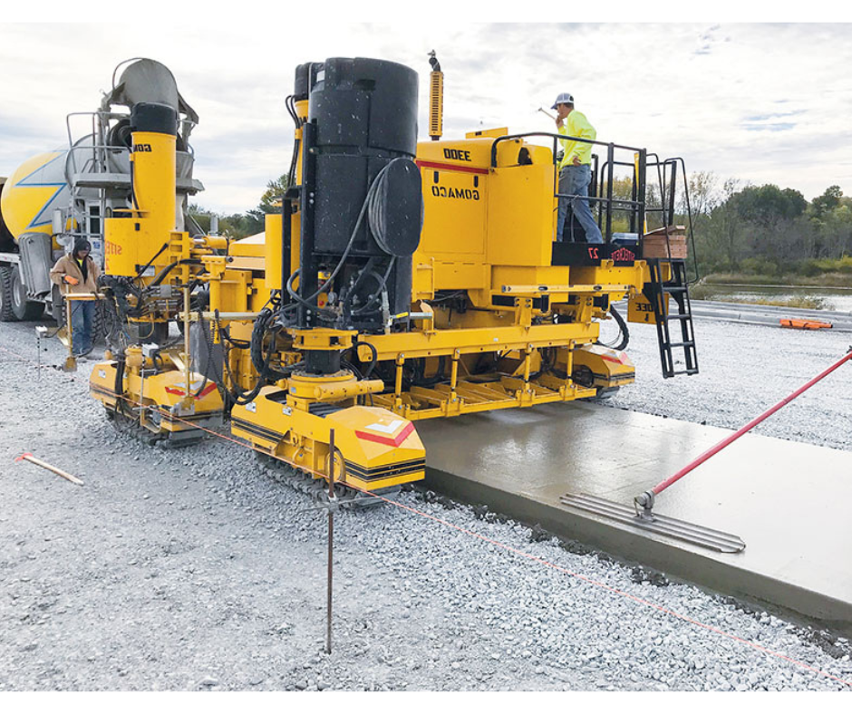Yellow paving machine on a construction site with workers around