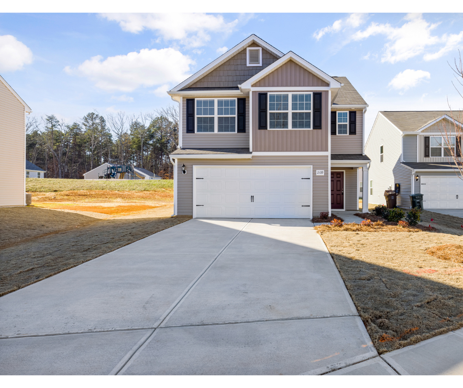 Two-story house with a garage and driveway in a suburban neighborhood.