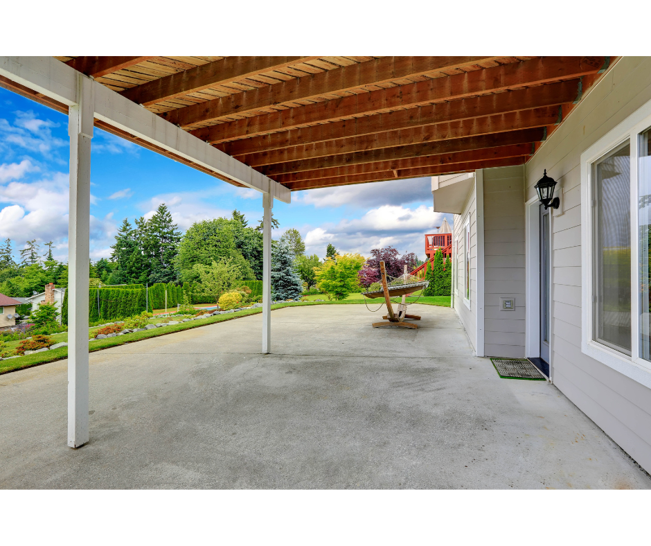 Covered patio area with wooden ceiling, concrete floor, and garden view.