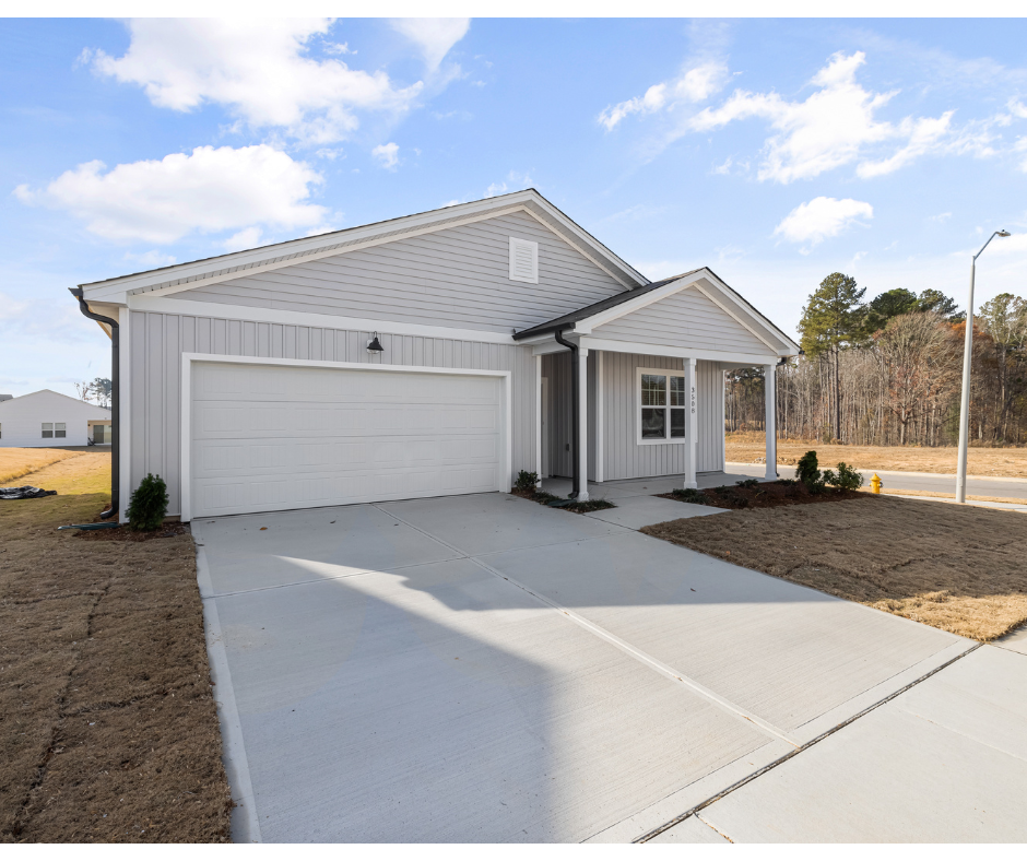 Single-story house with a garage and concrete driveway under a blue sky.